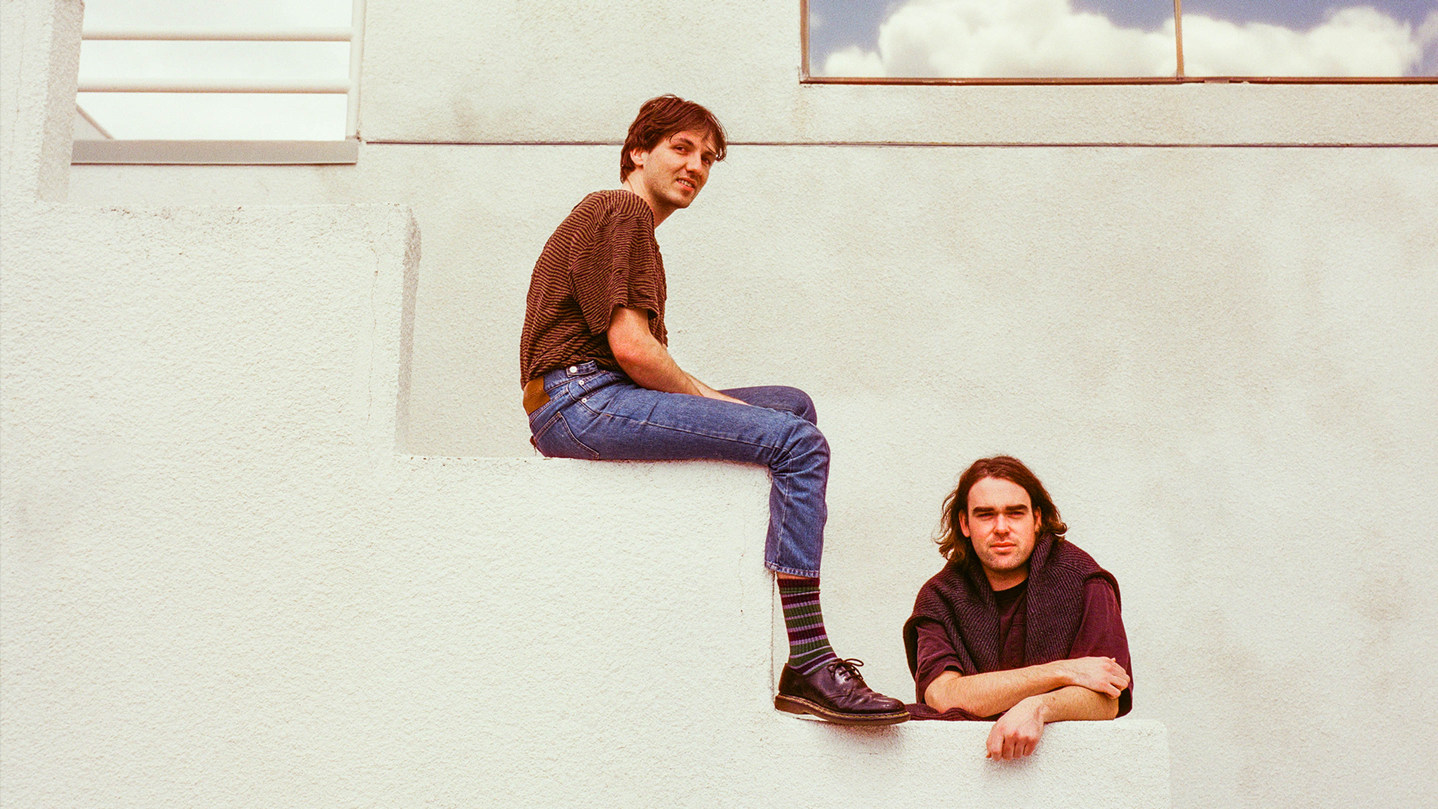 Two band members of Good Morning sitting and leaning on large stairs.