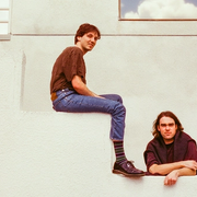 Two band members of Good Morning sitting and leaning on large stairs.