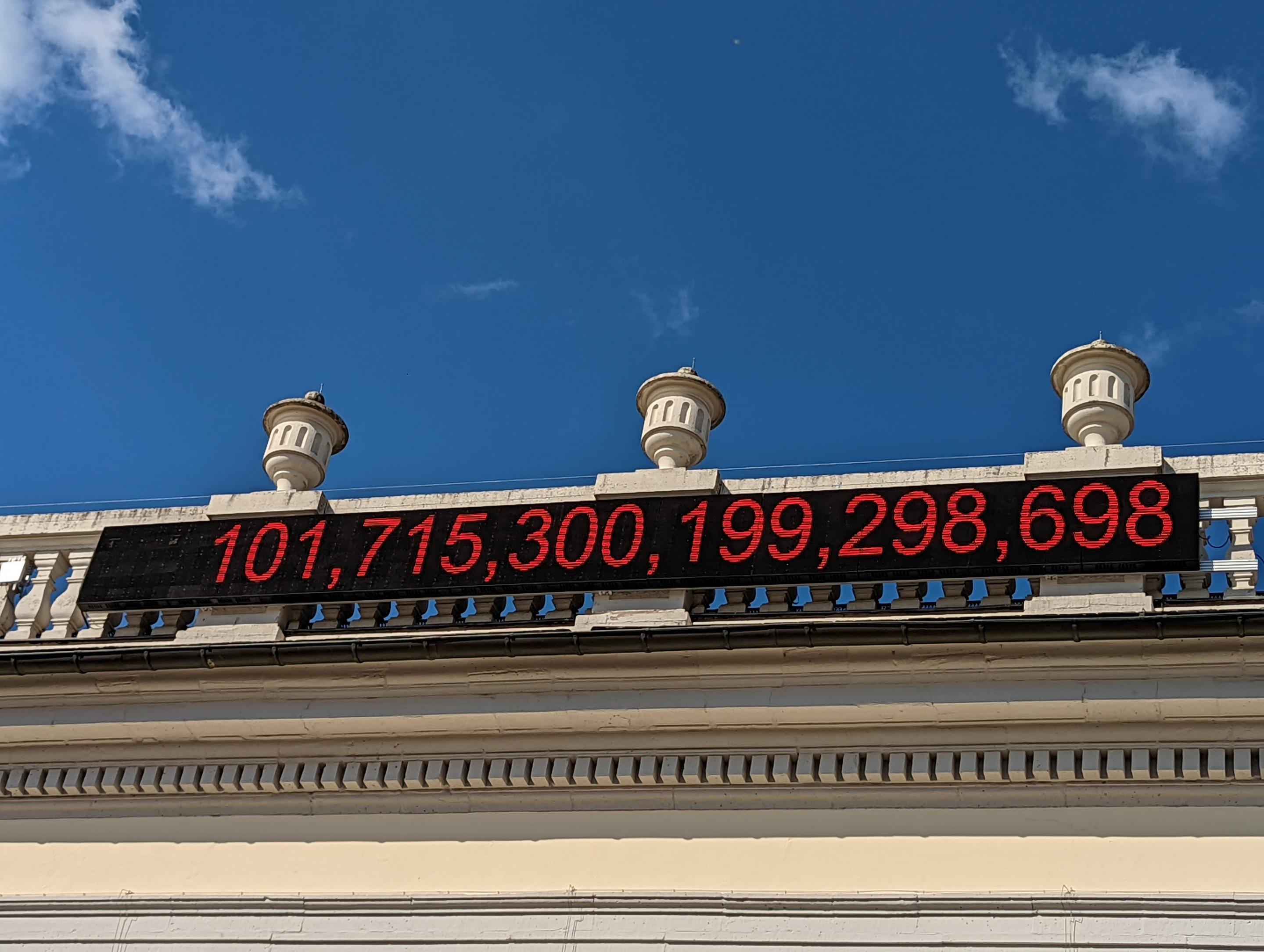 A digital clock shows the total showing over 1000 trillion dollars on a a colonial building